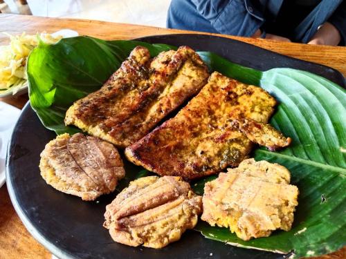 a plate of food with meat on a plate with leaves at Cabañas Guacari San Agustín huila in San Agustín
