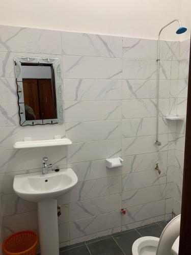 a white bathroom with a sink and a mirror at Peaceful Stay 2SR in Cotonou