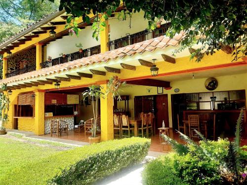 Casa amarilla con patio con mesa y sillas en Posada La Querencia, en Xico