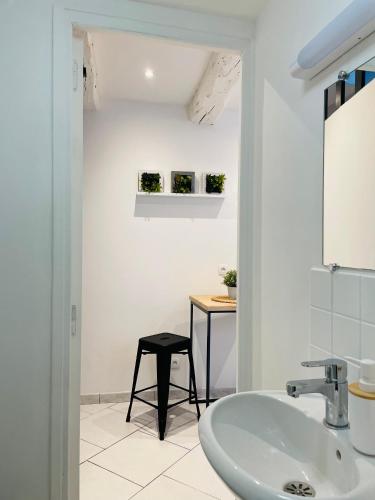a white bathroom with a sink and a stool at BE MY APPARTS, Studio de charme "LE COSY", DOUAI, Coeur de ville in Douai