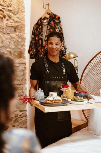 a man holding a tray of food on a table at Amarla Boutique Hotel Casco Viejo in Panama City