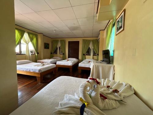 a hotel room with three beds and a tv at Hotel Sierpe River- Oleaje Sereno in Sierpe