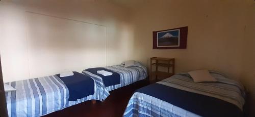Habitación con 2 camas y una foto en la pared. en Orkkowasi backpackers, en Arequipa