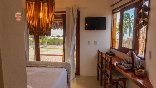 a bedroom with a bed and a desk with a window at Villa Kabaceiras in Tatajuba