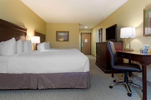 a hotel room with a bed and a desk with a computer at Best Western Plus Grand-Sault Hotel & Suites in Grand Falls