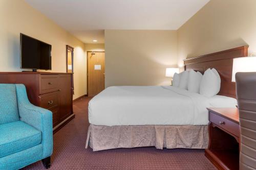 a hotel room with a bed and a blue chair at Best Western Plus Fredericton Hotel & Suites in Fredericton