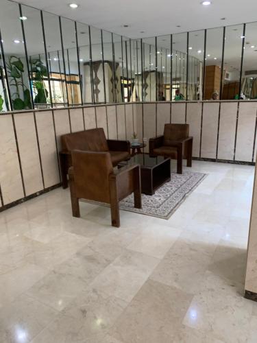 eine Lobby mit 2 Stühlen, einem Tisch und Spiegeln in der Unterkunft Charmant appartement pour famille uniquement en résidence à Oran Gambetta in Oran