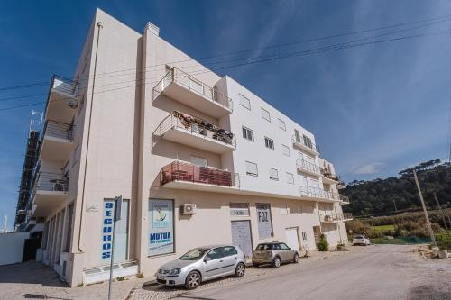 a white building with two cars parked in front of it at Farol Beach Place in Nazaré