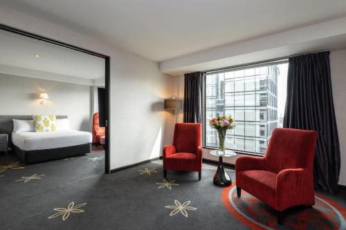 a hotel room with a bed and two chairs and a mirror at SkyCity Hotel Auckland in Auckland