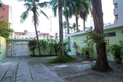 a parking lot with palm trees and a garage at Pousada Aloha Cantinho in Guarujá