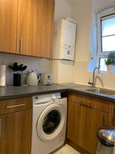 uma cozinha com uma máquina de lavar roupa e um lavatório em New look flat In Waterloo em Londres