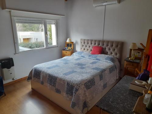 Un dormitorio con una cama con edredón azul y una ventana. en zona Uncas, en Tandil