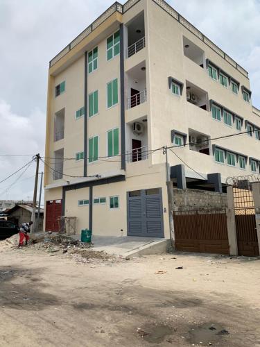 a large white building with green windows and a parking lot at Peaceful Stay 1SR in Cotonou
