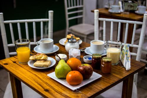 una mesa de madera con un desayuno de fruta y zumo en Hotel Estrella Andina en San Juan