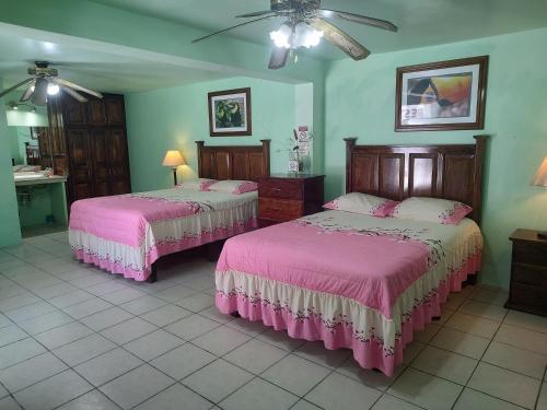 two beds in a room with pink sheets at Freedom Shores "La Gringa" Hotel - Universally Designed in Isla Aguada