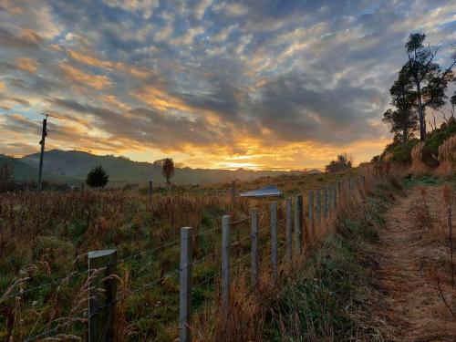 a fence next to a dirt road in a field at DuxHouse BnB in Taihape
