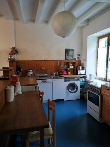 une cuisine avec une table et une machine à laver dans l'établissement Gite des petites ruelles : familial et chaleureux, à Trôo