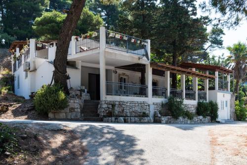 a white house with a porch and a tree at Apartments by the sea Cove Saplunara, Mljet - 4900 in Saplunara