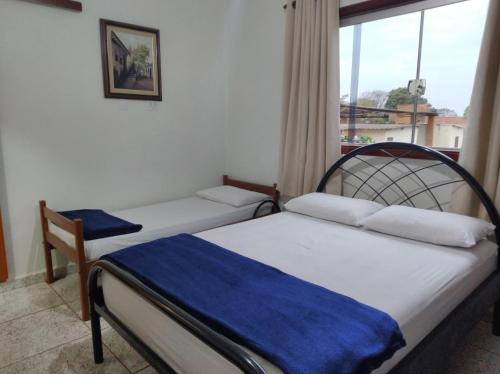 2 Betten in einem Zimmer mit Fenster in der Unterkunft Ana Terra Barretos Casa de Campo in Barretos