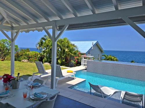 een patio met een tafel en stoelen naast een zwembad bij Blue Haven Villas Guadeloupe Villa Blue Star in Bouillante