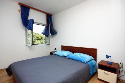 a bedroom with a bed with blue pillows and a window at Apartments by the sea Cove Saplunara, Mljet - 4914 in Saplunara