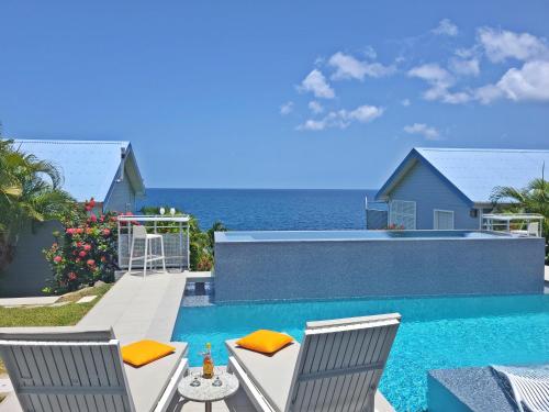 een zwembad met twee stoelen en de oceaan bij Blue Haven Villas Guadeloupe Villa Blue Star in Bouillante