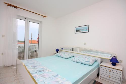 ein weißes Schlafzimmer mit einem Bett und einem Fenster in der Unterkunft Apartments with parking spaces Barbat, Rab - 4962 in Rab