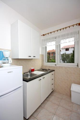 a kitchen with white cabinets and a sink at Apartments with parking space Barbat, Rab - 4962 in Rab