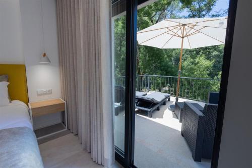 ein Schlafzimmer mit einem Bett und einem Balkon mit einem Sonnenschirm in der Unterkunft Be Alva in Oliveira do Hospital