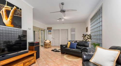 a living room with a flat screen tv and leather furniture at Seabreeze - Minutes from the Beach in Tootgarook