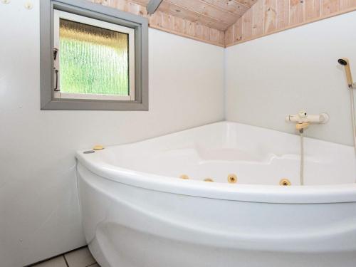La salle de bains est pourvue d'une baignoire blanche et d'une fenêtre. dans l'établissement 8 person holiday home in Sydals, à Sarup