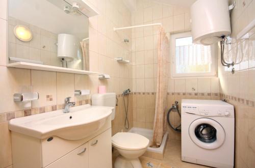 a bathroom with a toilet sink and a washing machine at Apartments by the sea Barbat, Rab - 5005 in Barbat na Rabu