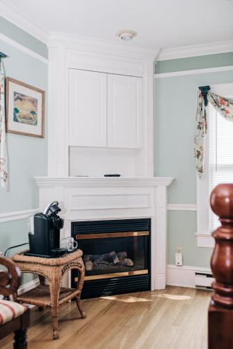 a living room with a fireplace and a chair at Benn Conger Inn in Groton