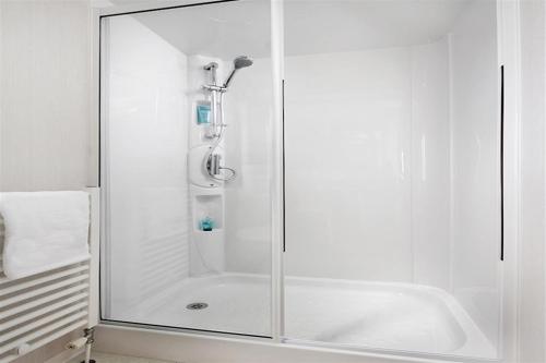 a shower with a glass door in a bathroom at Caravan on Fantastic site in Dunbar