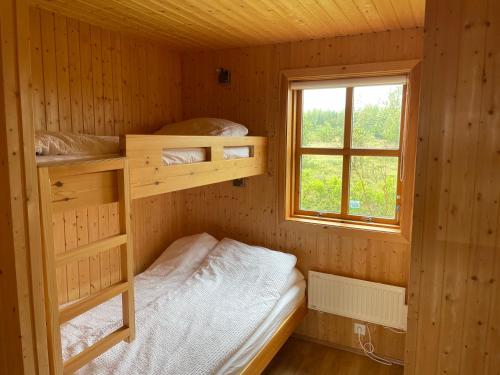 Cette petite chambre comprend des lits superposés et une fenêtre. dans l'établissement Aurora Cottage on the Golden Circle, à Selfoss
