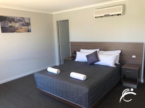 a bedroom with a bed with two pillows on it at Coro Club Motel in Griffith