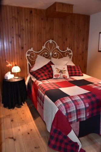 a bedroom with a bed with a checkered blanket at PETIT COIN DE PARADIS in Sainte Anne des Lacs