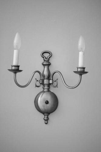a metal chandelier with three candles on a wall at Benn Conger Inn in Groton