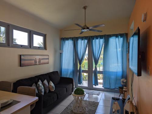 a living room with a black couch and blue curtains at Beautiful Ocean Front Villa in Aguada