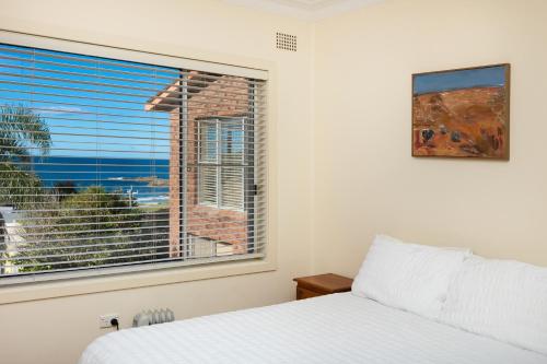 a bedroom with a bed and a large window at Palm Road in Forster