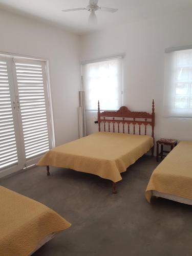 a bedroom with two beds and two windows at Casa da Barra Delfinopolis in Delfinópolis