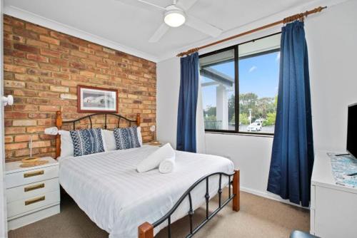 a bedroom with a bed and a brick wall at Byron Bay Accom Unit 6 70 Lawson Street - Atlantis in Byron Bay