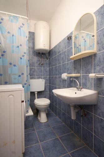 a blue tiled bathroom with a sink and a toilet at Apartments with a parking space Rukavac, Vis - 8849 in Vis