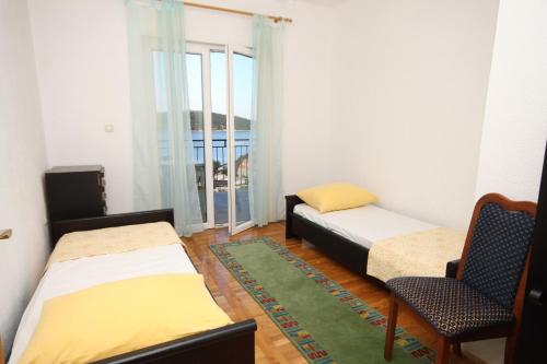 a room with two beds and a chair and a window at Apartments by the sea Necujam, Solta - 8647 in Grohote