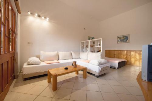 een woonkamer met een witte bank en een tafel bij Apartments and rooms with parking space Komiza, Vis - 8844 in Komiža