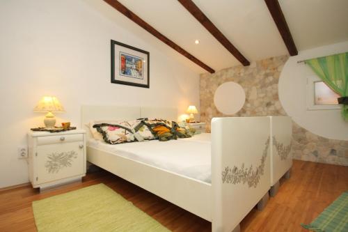 a white bedroom with a bed and a night stand at Apartments with a parking space Rukavac, Vis - 8859 in Vis