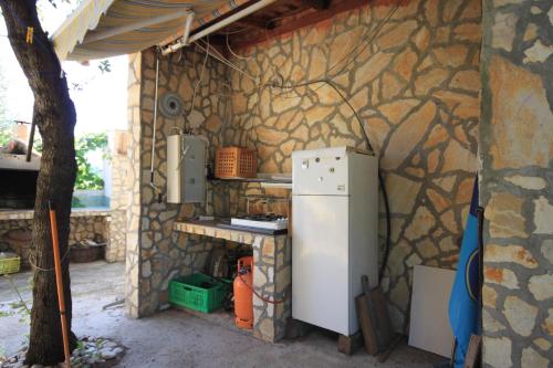 a kitchen with a refrigerator and a stone wall at Apartment Rukavac 8864b in Rukavac