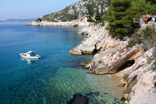 een boot in het water naast een rotsachtige kust bij Rooms with a parking space Trsteno, Dubrovnik - 8595 in Trsteno