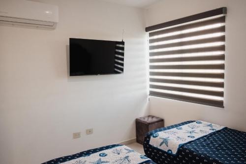 a bedroom with a bed and a flat screen tv at Amplio, hermoso, cómodo depa en Mazatlán in Mazatlán