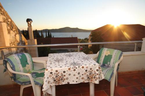 a table and chairs on a balcony with the sunset at Apartments with a parking space Trsteno, Dubrovnik - 8594 in Trsteno